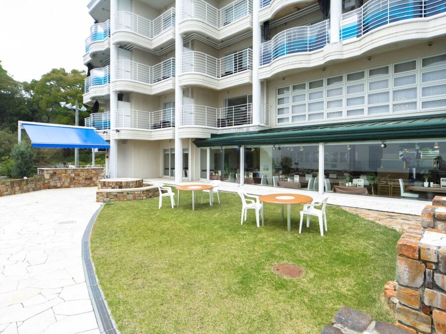 A multi-story hotel with outdoor seating and a stone wall.