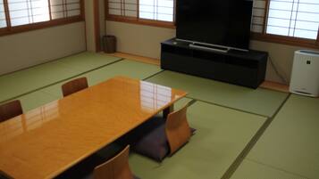 Um quarto japonês tradicional com tatames, uma mesa de madeira e uma televisão sobre um suporte.