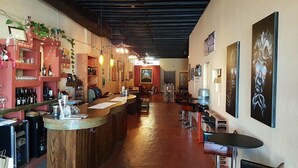 A bar area with a long counter, shelves with bottles, and a few chairs. There are paintings on the walls and a ceiling with exposed beams. - Cottonwood Hotel (Cottonwood)