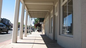 A covered sidewalk leading to a building with large windows and a sign for 'CINNABAR BOUTIQUE'. - Cottonwood Hotel (Cottonwood)