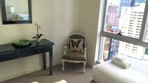 Une chambre d’hôtel équipée d’un lit, d’une chaise, d’un bureau, d’un miroir et d’une fenêtre donnant sur la ville.