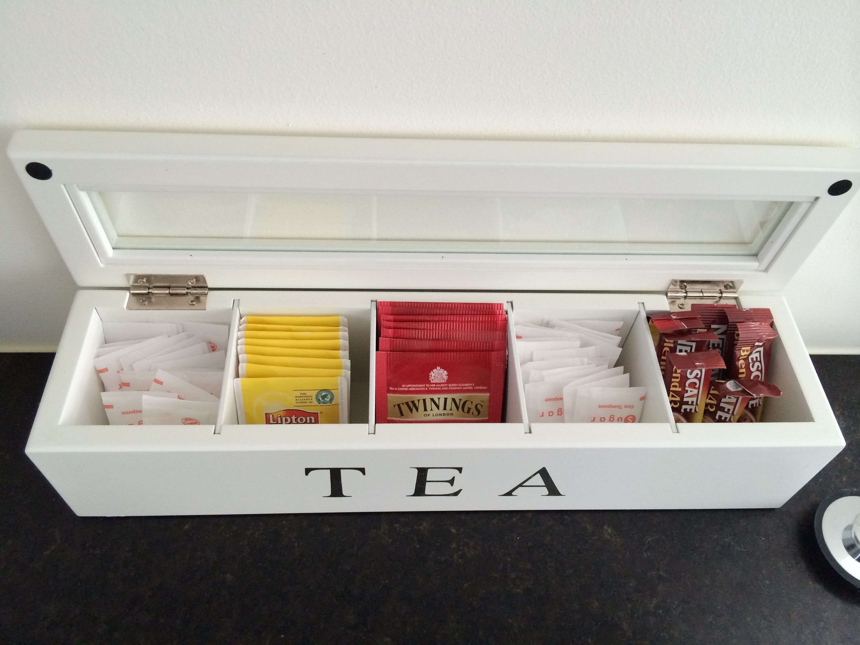Une boîte blanche portant l’inscription « THÉ » et contenant différents sachets de thé.