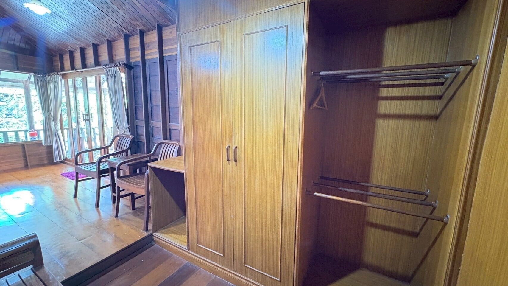 Un intérieur en bois comprenant un placard, un étendoir et un coin salon avec des chaises.
