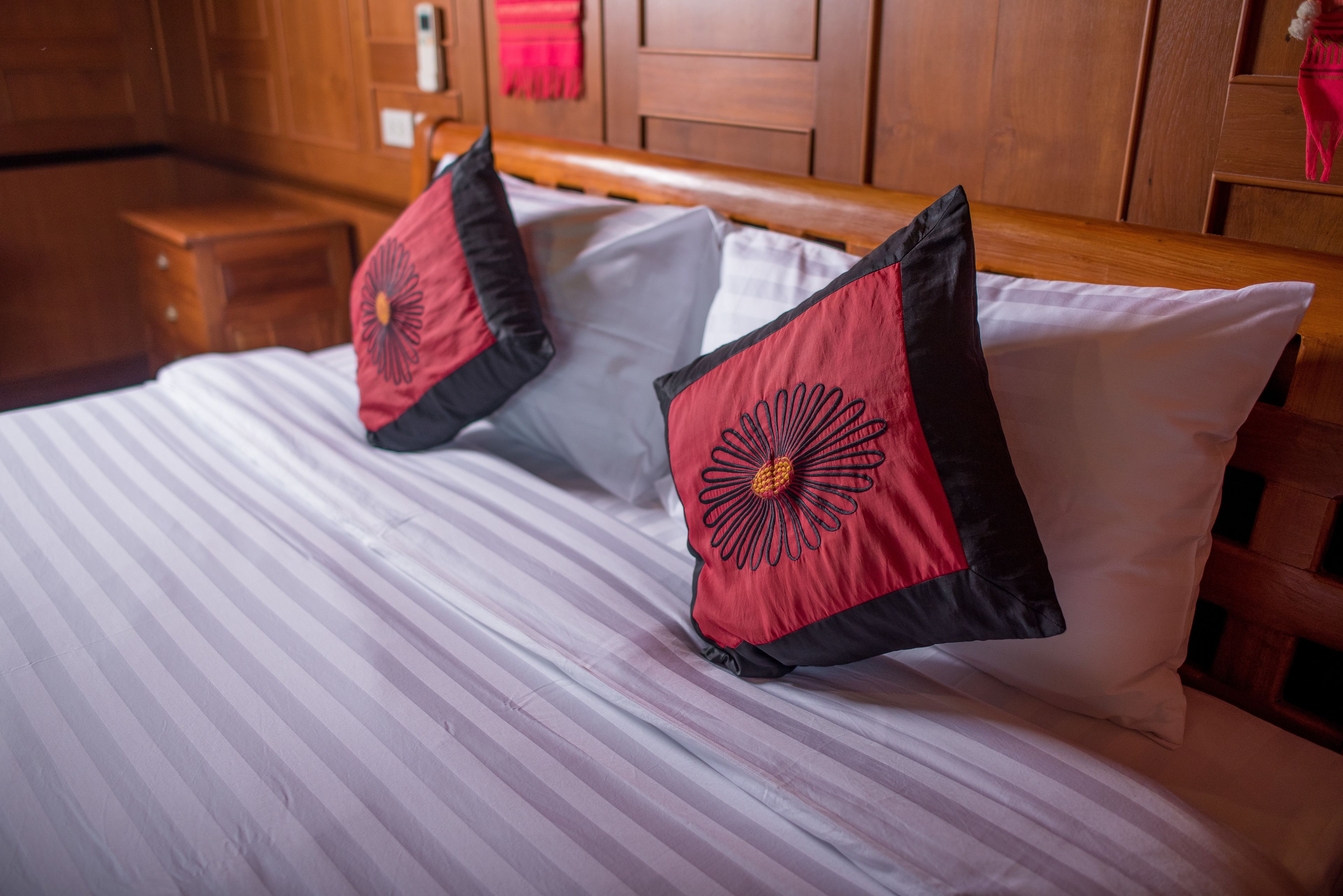 Una cama con ropa de cama a rayas y dos almohadas con diseño rojo y negro.