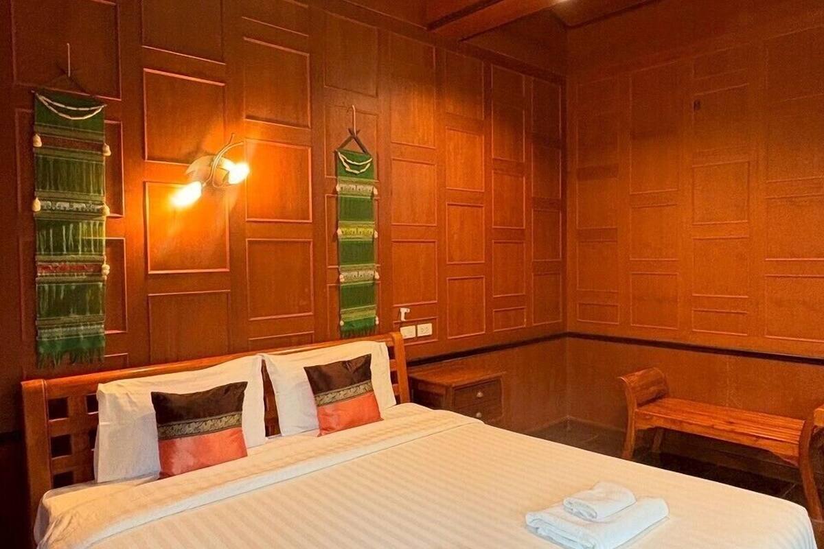A hotel room with a large bed, wooden panel walls, and a hanging light fixture.