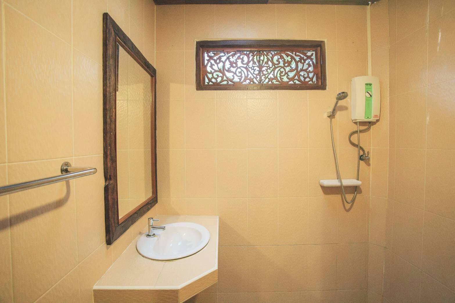 Casa de banho com lavatório, espelho, chuveiro e janela decorativa.