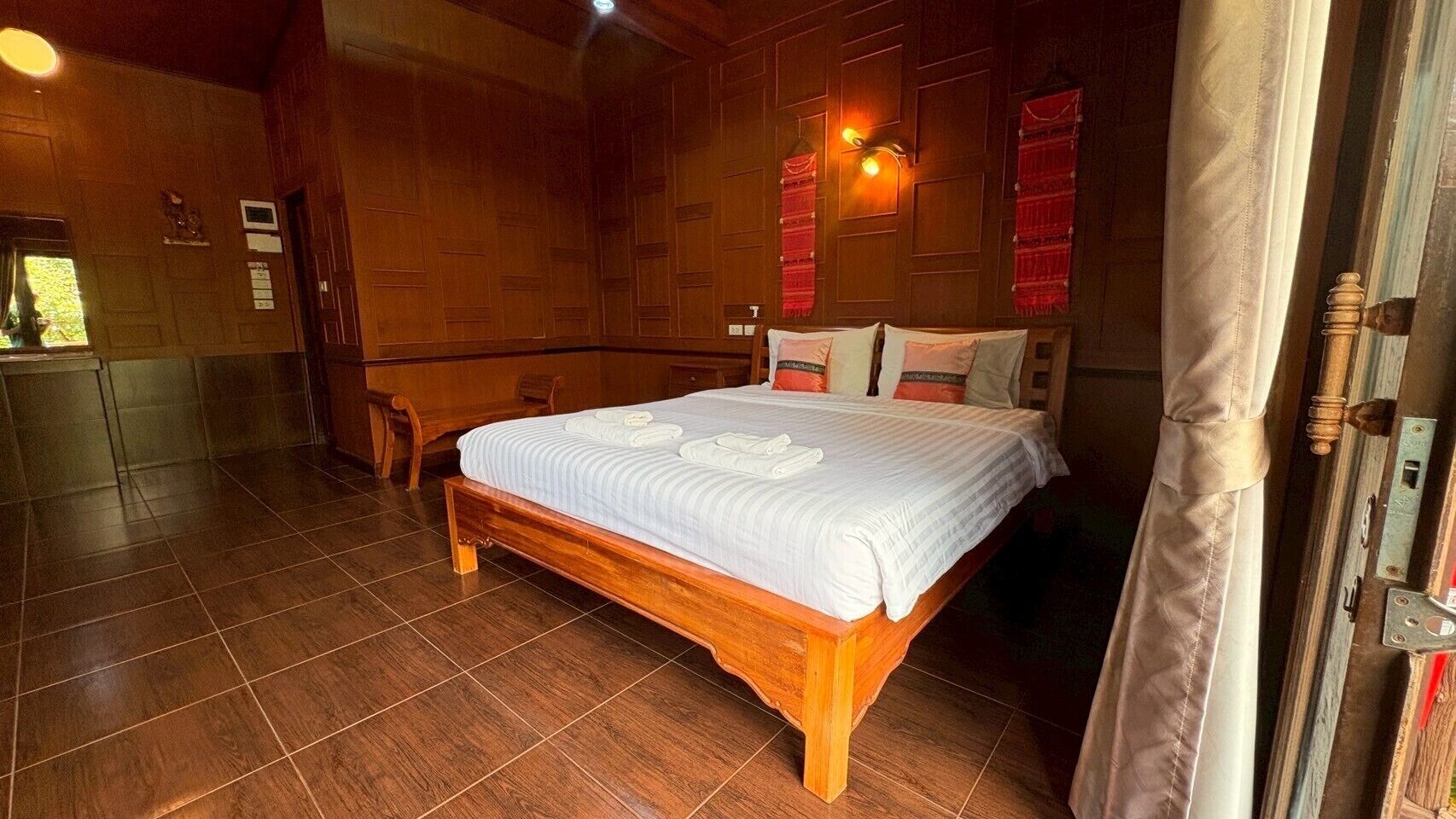 Una cama de madera en una habitación con suelo de baldosas y paredes de madera.