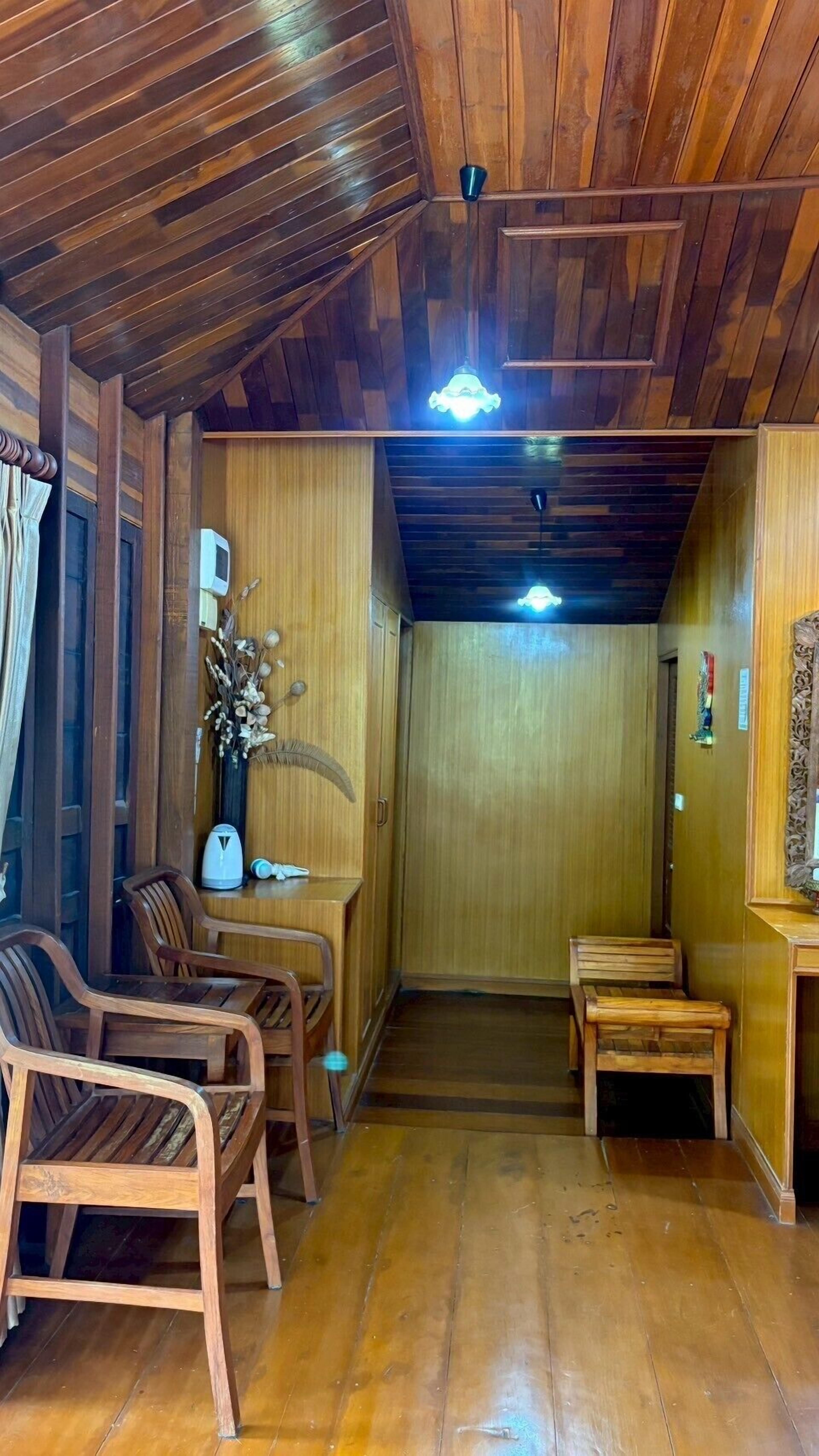 Ein Zimmer mit Holzboden, Holztäfelung, einer Holztür und einem kleinen Tisch mit Stühlen.