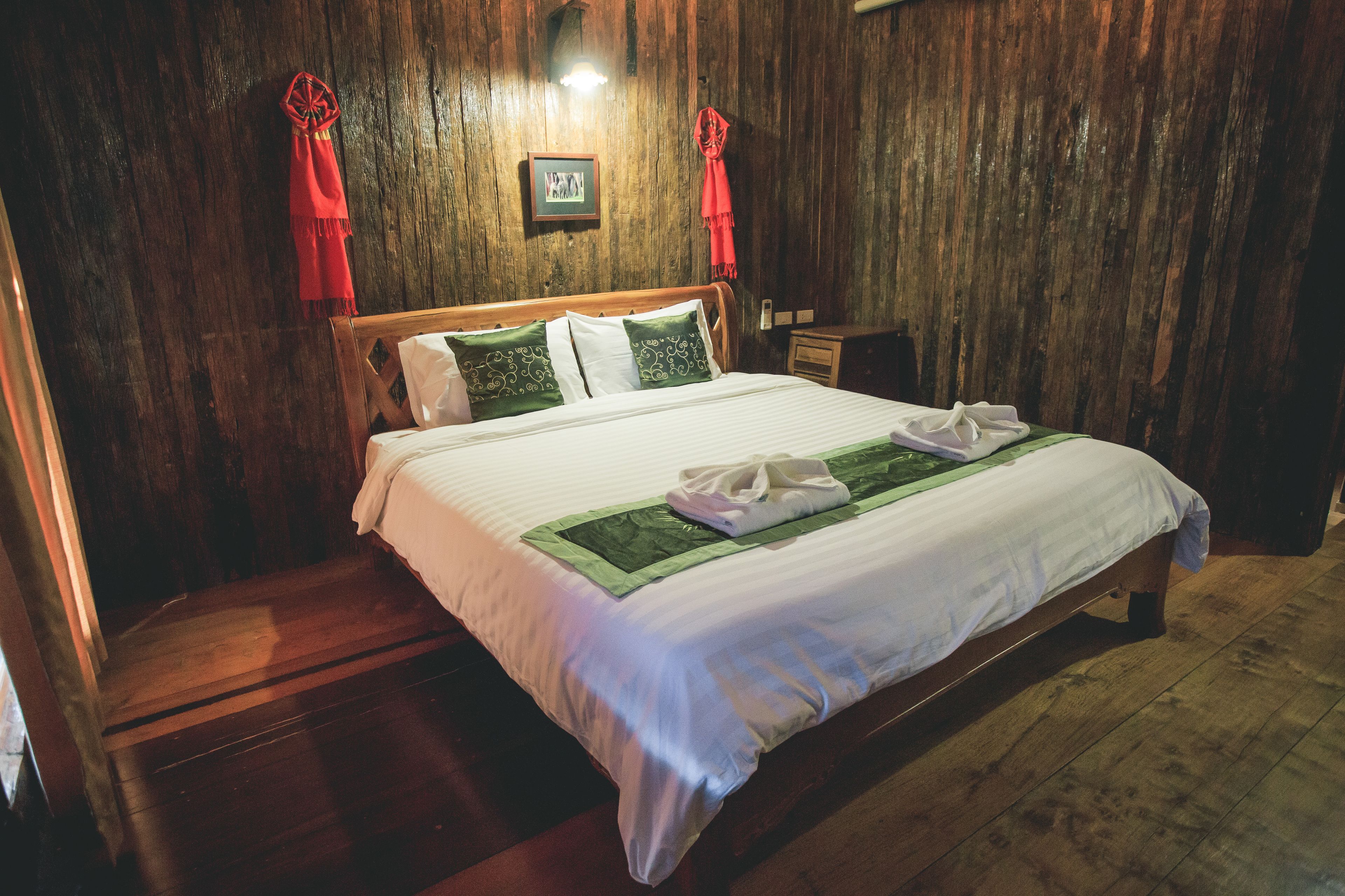 A wooden-paneled room with a bed, a nightstand, and a framed picture on the wall.