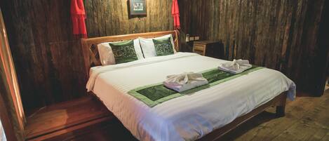 A wooden-paneled room with a bed, a nightstand, and a framed picture on the wall.