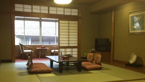 A traditional Japanese room with tatami flooring, a low table, and a television. - Sento Ryokan (Toyooka)