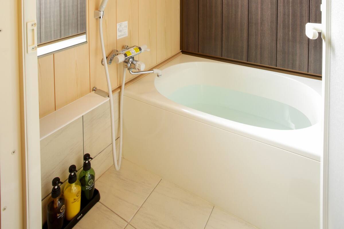 A bathroom with a bathtub, a mirror, a shower, and wooden paneling on the walls.