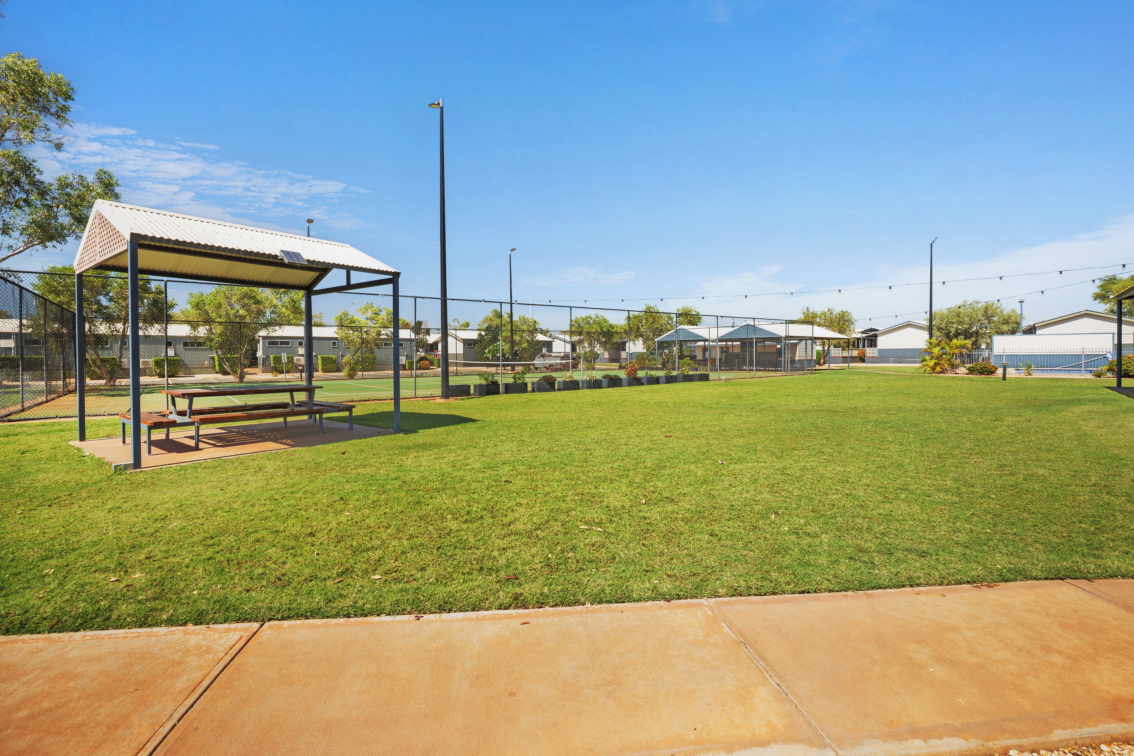 A grassy sports field with a picnic table and a covered seating area.