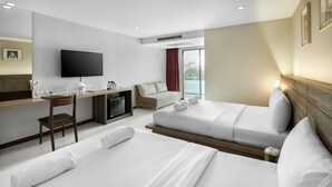 Habitación de hotel con dos camas, un escritorio, televisión y vista a la ciudad.