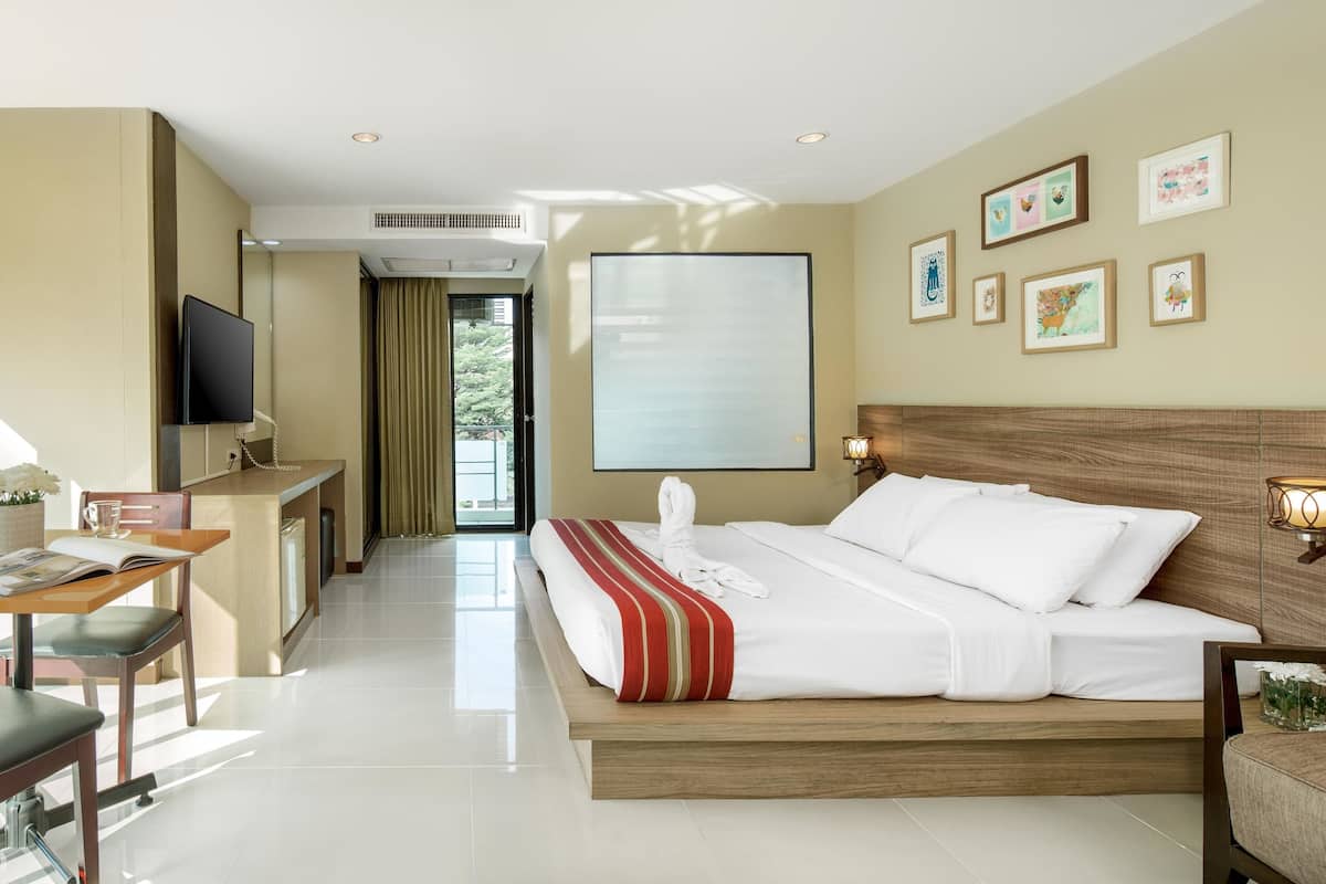 A hotel room with a bed, a desk, a chair, a TV, and a view of the outdoors.