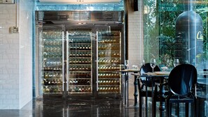 Un interior moderno con una bodega de vino, una vitrina de vidrio y un comedor con sillas y una mesa.