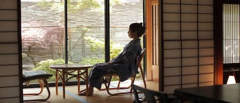 A traditional Japanese room with tatami flooring, a low table, and a sliding door leading to a garden.