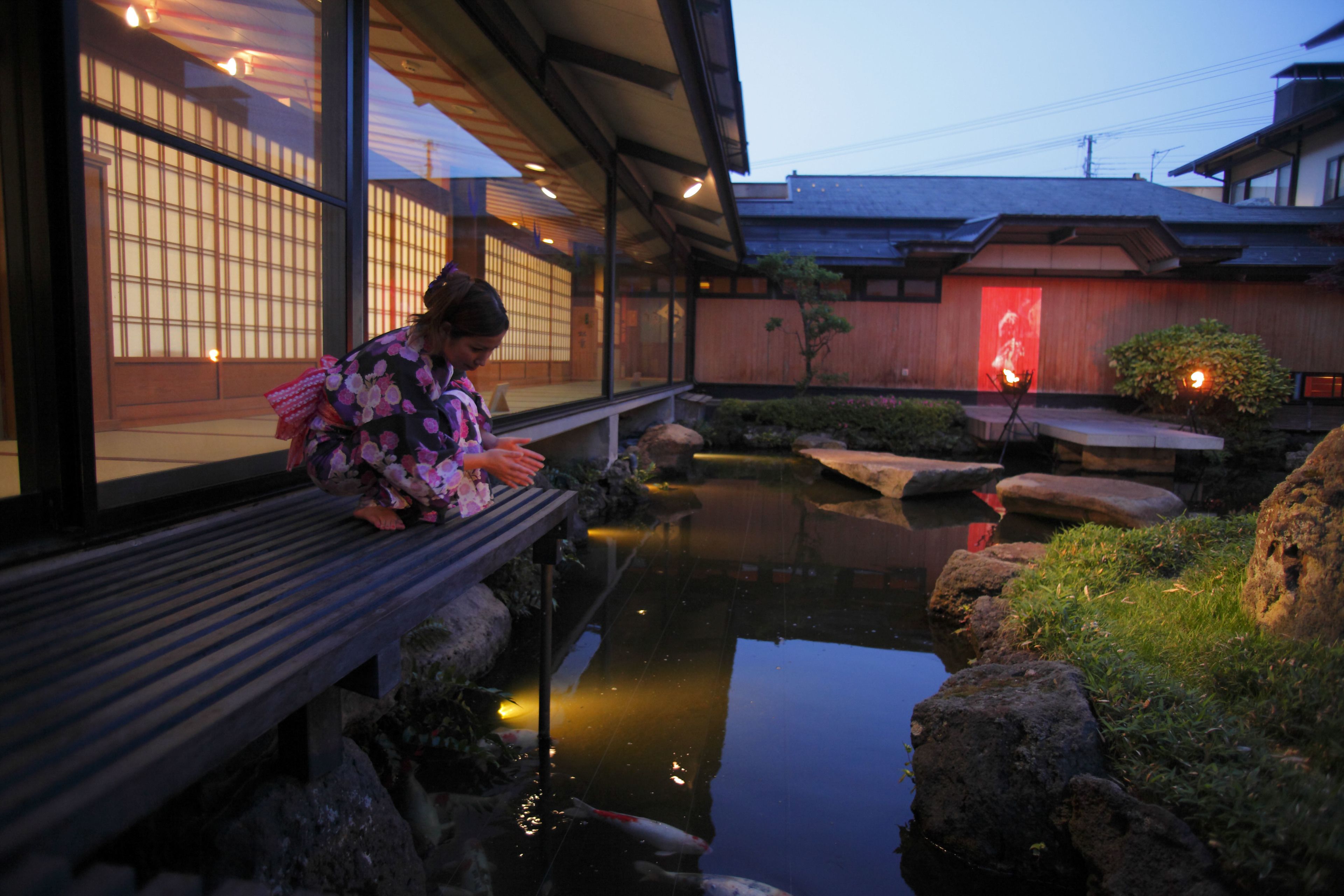 A traditional Japanese garden with a koi pond, wooden benches, and a stone lantern.