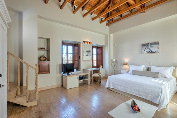 A bedroom with a bed, desk, chair, and a television. - Mare Monte Luxury Suites (Spetses)