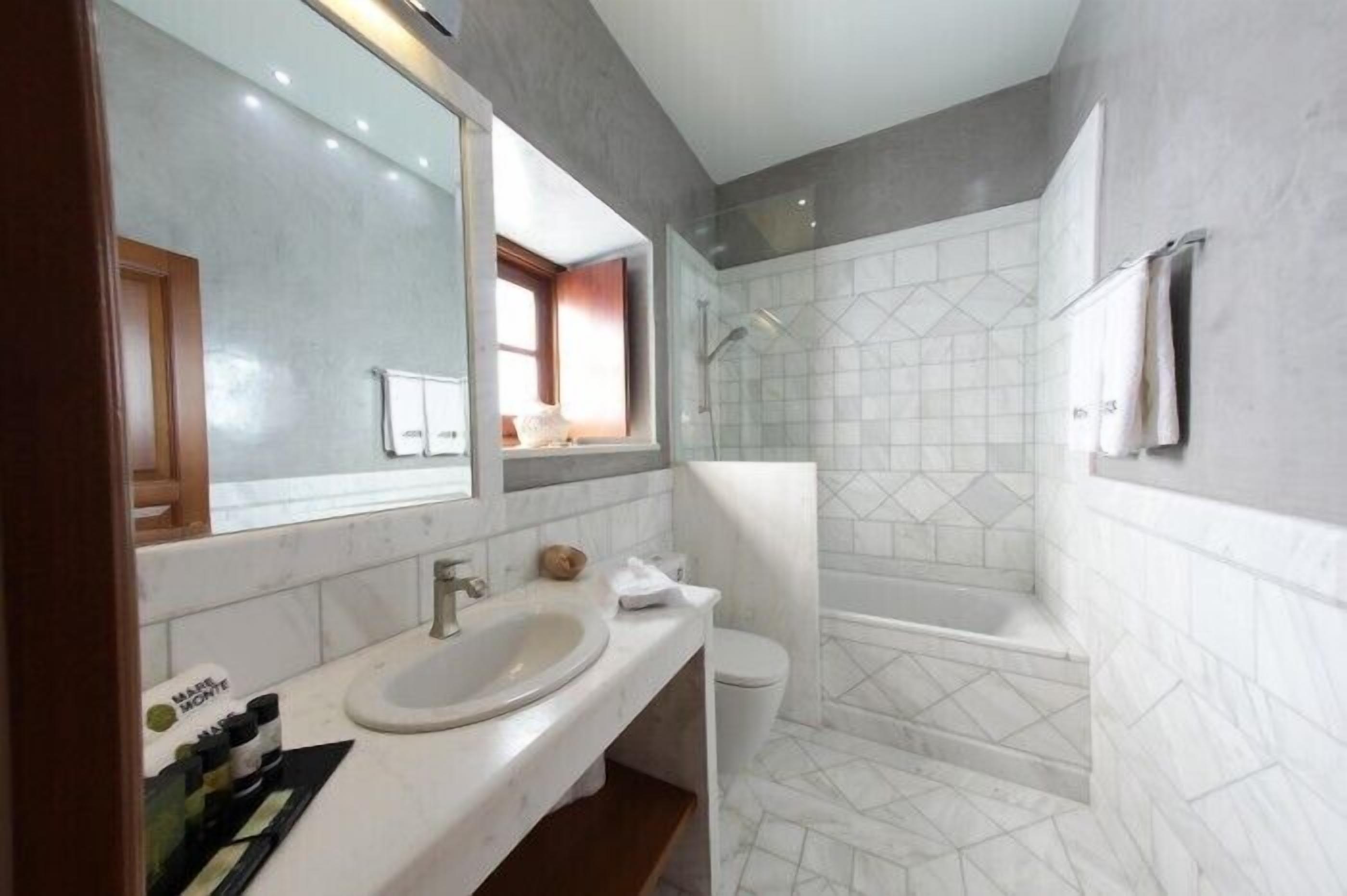 A modern bathroom with a large mirror, a sink, a toilet, and a shower area.