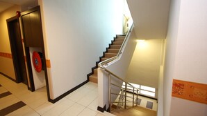 A staircase with a handrail, a door with a red handle, and a patterned wall. - 1 City Hotel (Kota Kinabalu)