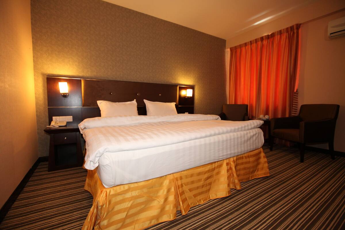 Ein Hotelzimmer mit einem großen Bett, zwei Nachttischen, einem Schreibtisch und einem Stuhl.