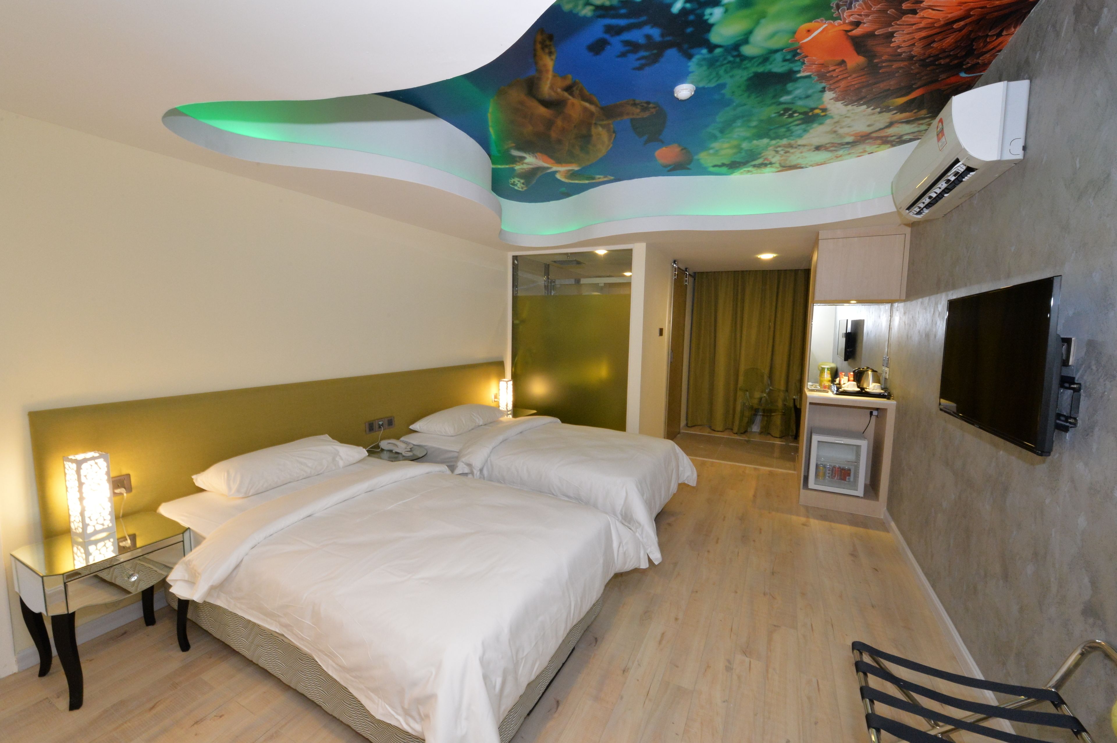A hotel room with two beds, a ceiling mural, a TV, and a minibar.