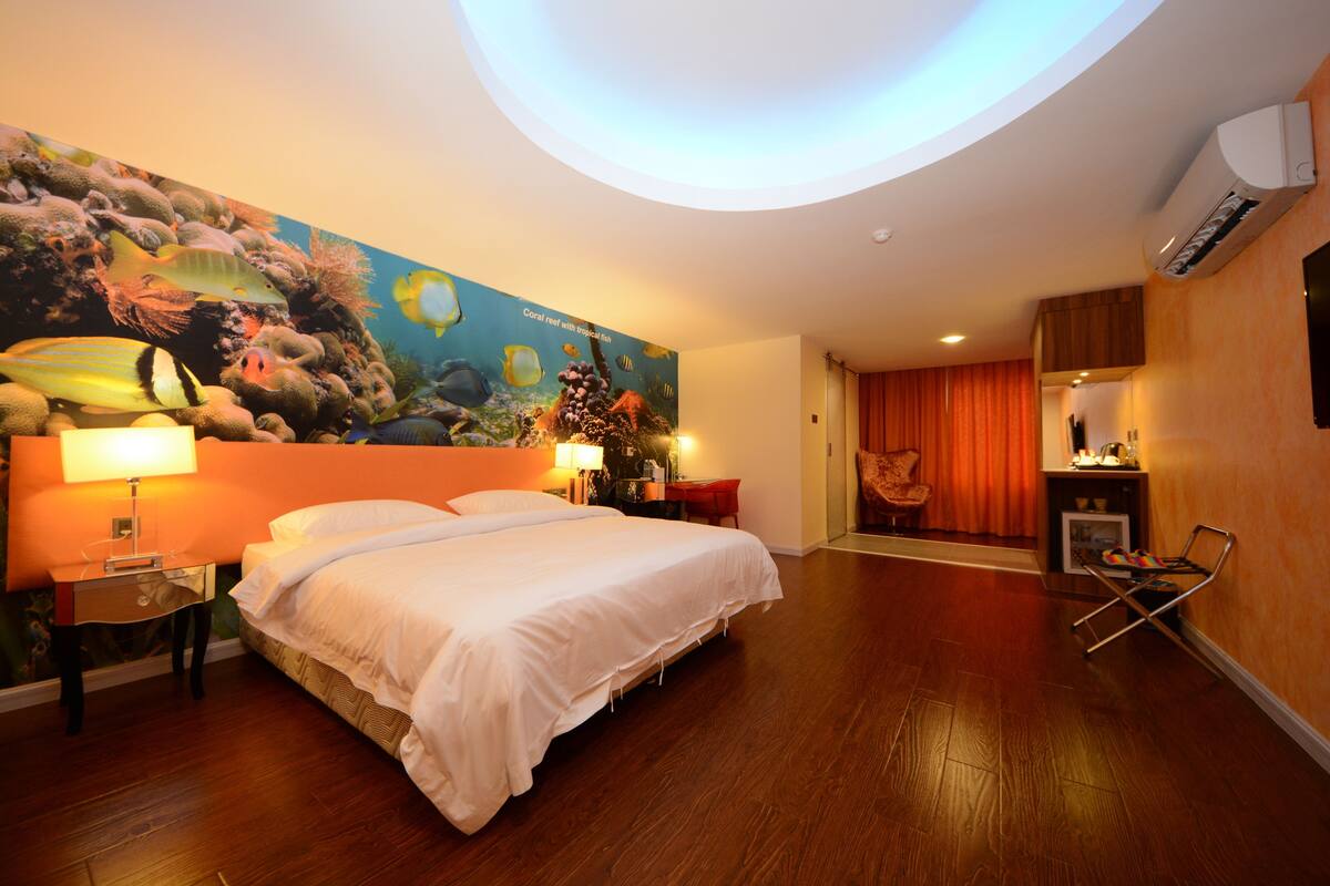 Habitación de hotel con cama, escritorio, silla y un mural grande de una escena submarina.