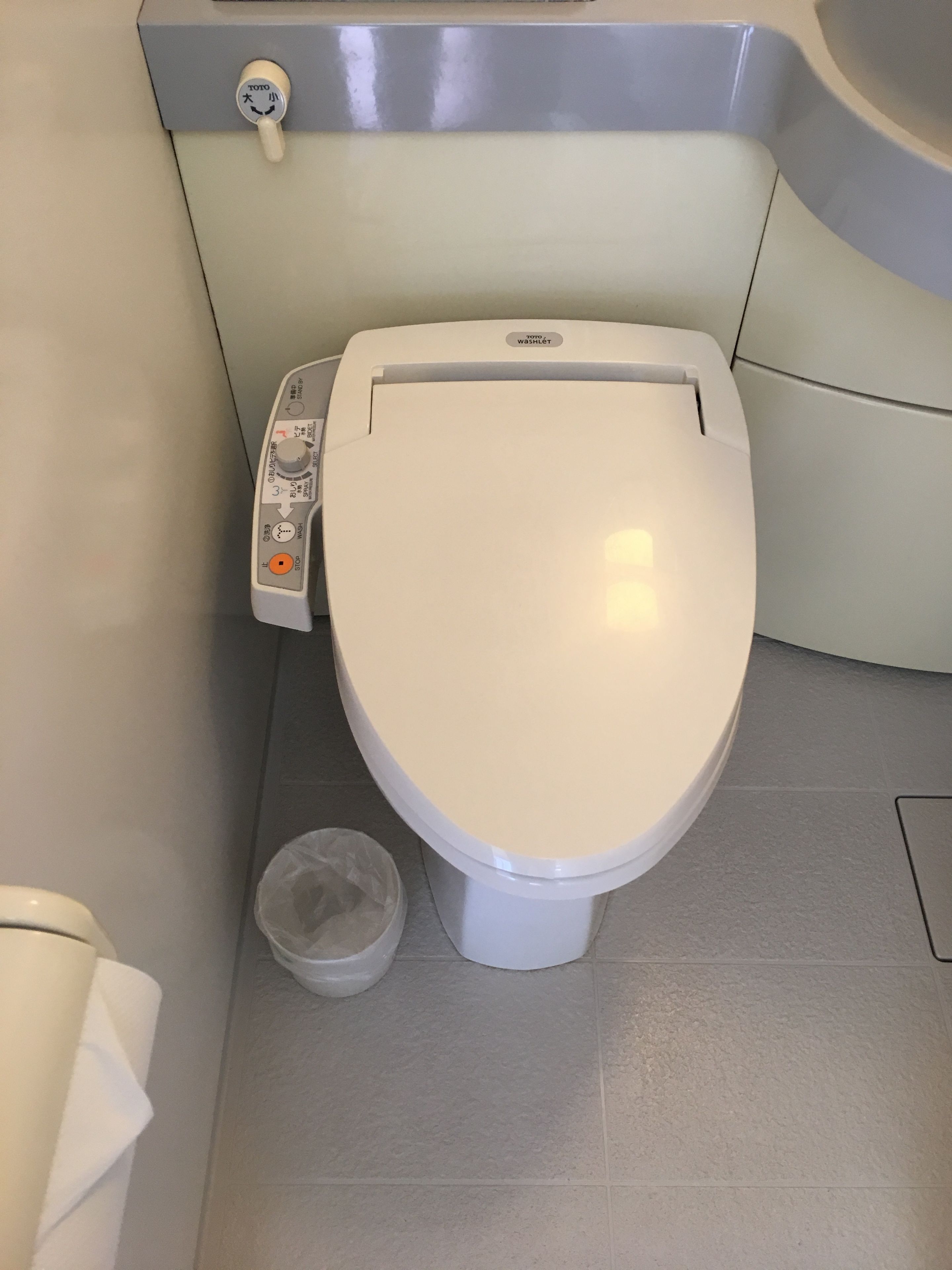 Des toilettes modernes dotées d’un panneau de commande, d’un accessoire de type bidet et d’une poubelle.