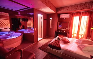 A hotel room with a bed, a bathtub, a mirror, and a vanity with a sink.