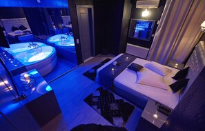 A modern hotel room with a large bed, a separate bathroom with a bathtub, and a television mounted on the wall. - Atlantic Hotel (Kallithea)