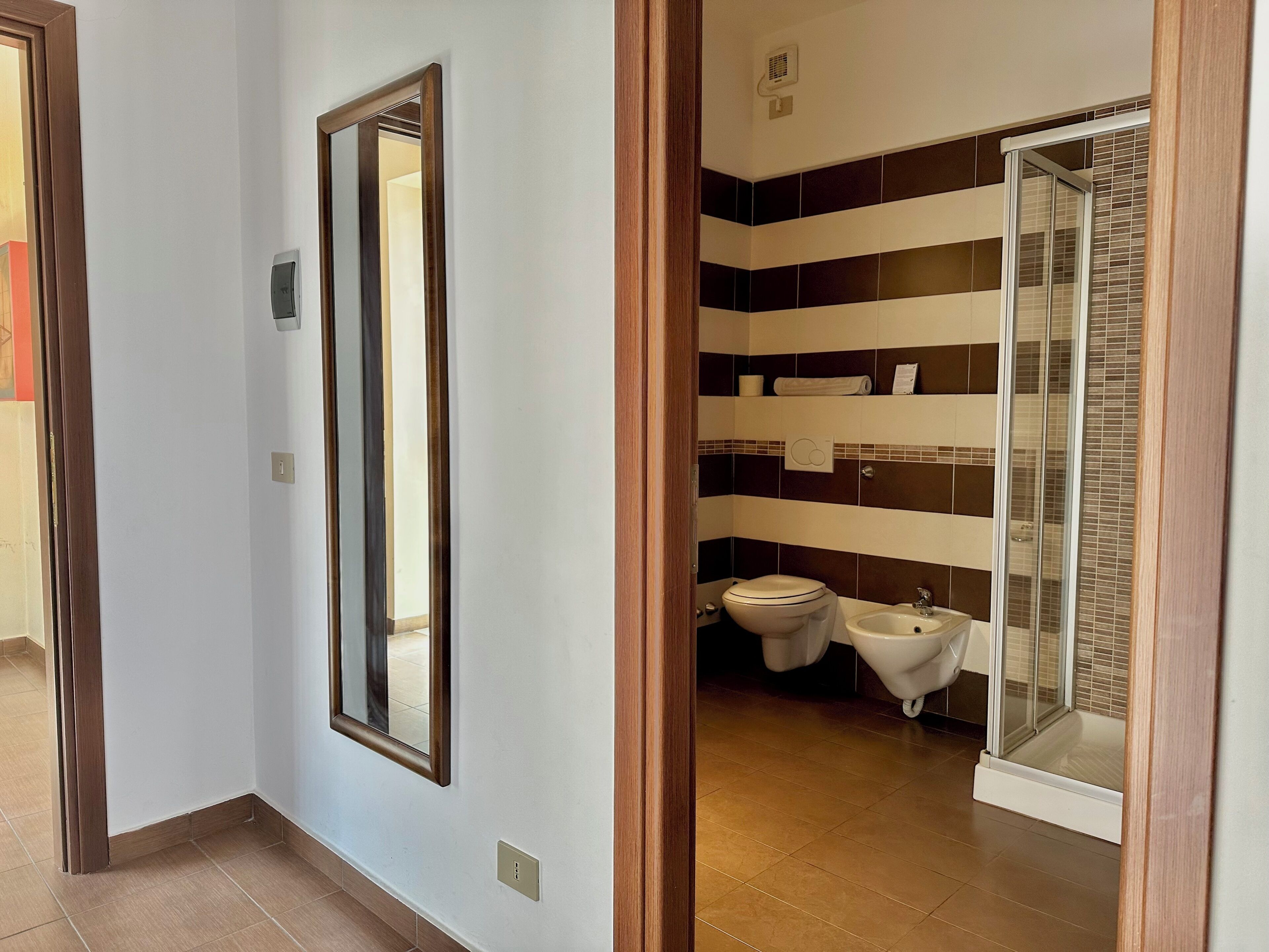 Une salle de bain équipée de toilettes, d’un bidet et d’une douche à parois en verre.