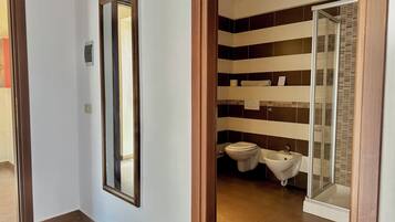 Une salle de bain équipée de toilettes, d’un bidet et d’une douche à parois en verre.