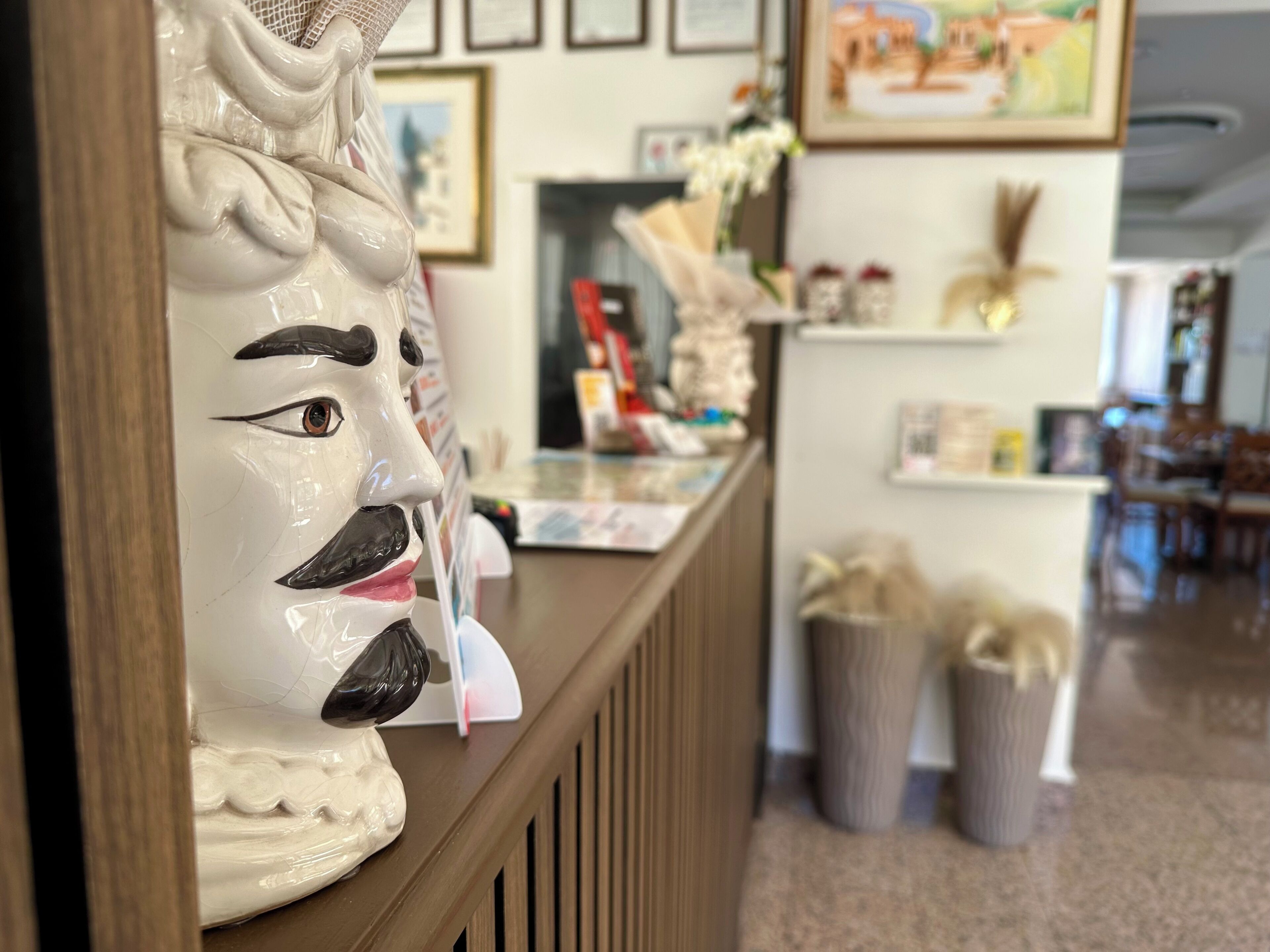 Un'area reception con una decorativa testa in ceramica, un bancone con diversi oggetti e un quadro appeso al muro.