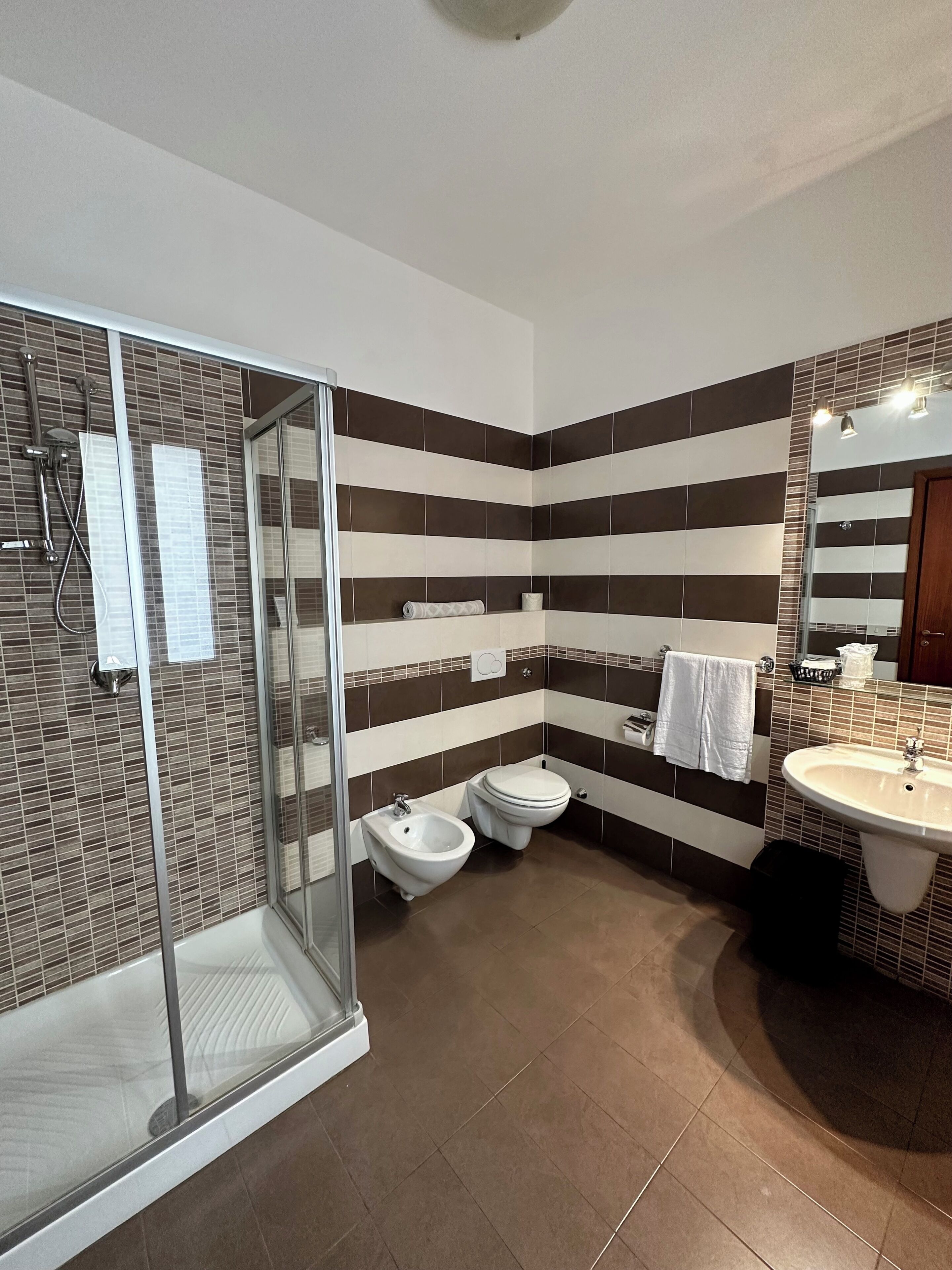 Une salle de bain moderne équipée d’une douche, de toilettes, d’un bidet et d’un lavabo.