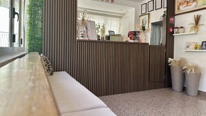 A reception area with a reception desk, a seating area, a wall-mounted sign reading 'RECEPTION,' and framed certificates on the wall. - Hotel Soleado (Taormina)