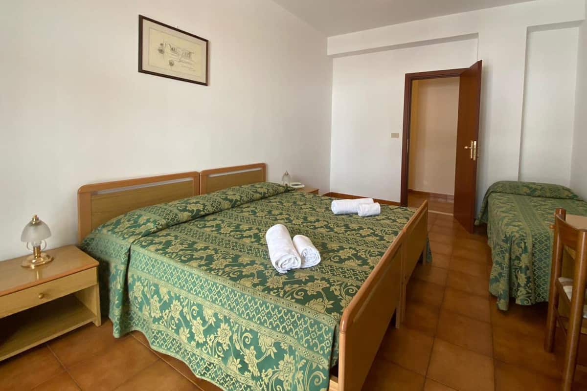 Habitación triple, balcón | Escritorio, cunas y ropa de cama
