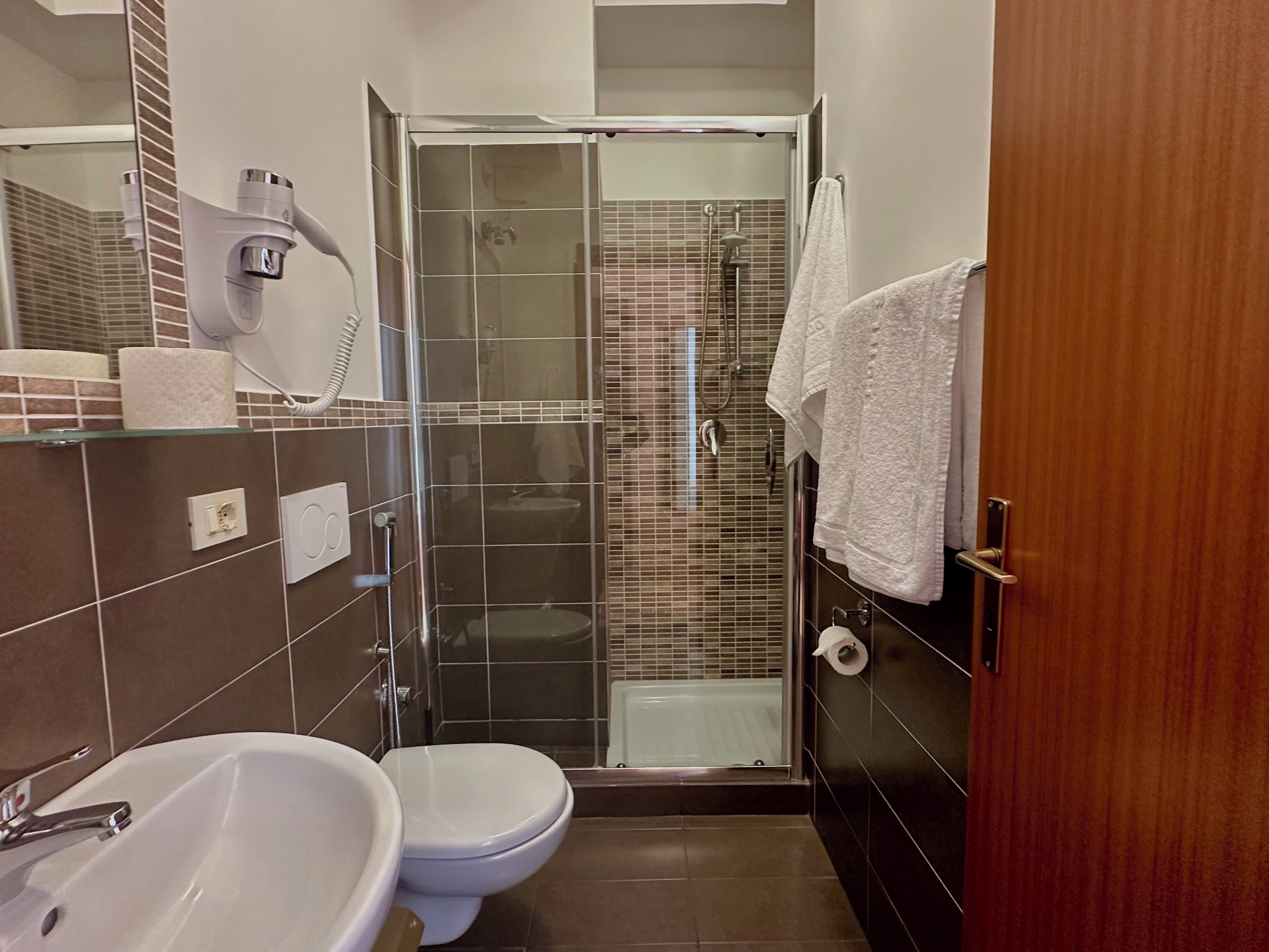 A bathroom with a glass-enclosed shower, a white sink, and a toilet.