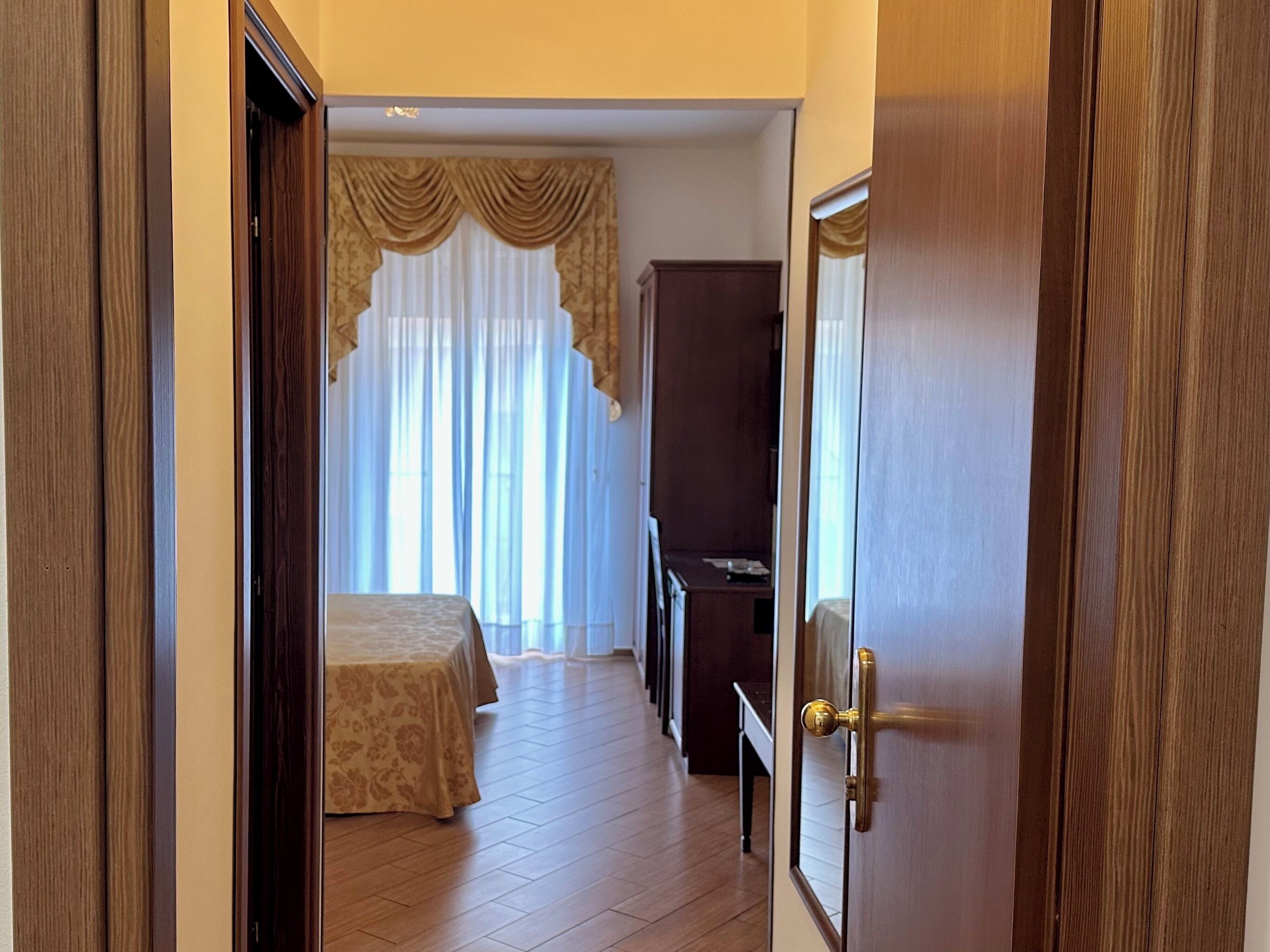 Ein Hotelzimmer mit Bett, Schrank und einer Tür mit Messinggriff.