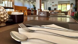 A dining table set with cutlery and a napkin, with a box labeled 'Malkano' in the background. - Hotel Soleado (Taormina)
