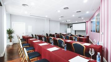 Ein Konferenzraum mit langen Tischen, Stühlen und einer Projektionsleinwand.