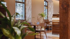 Un comedor moderno con muebles de madera, plantas en macetas y ventanas amplias.