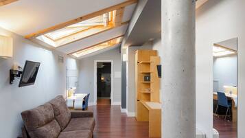 Un loft moderne avec des poutres en bois, un pilier en béton, un canapé et un espace bureau.