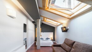 Un dormitorio moderno con tragaluz, una cama grande, un sofá y un televisor.