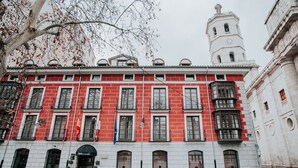 Un edificio rojo y blanco con múltiples ventanas y una torre del reloj.