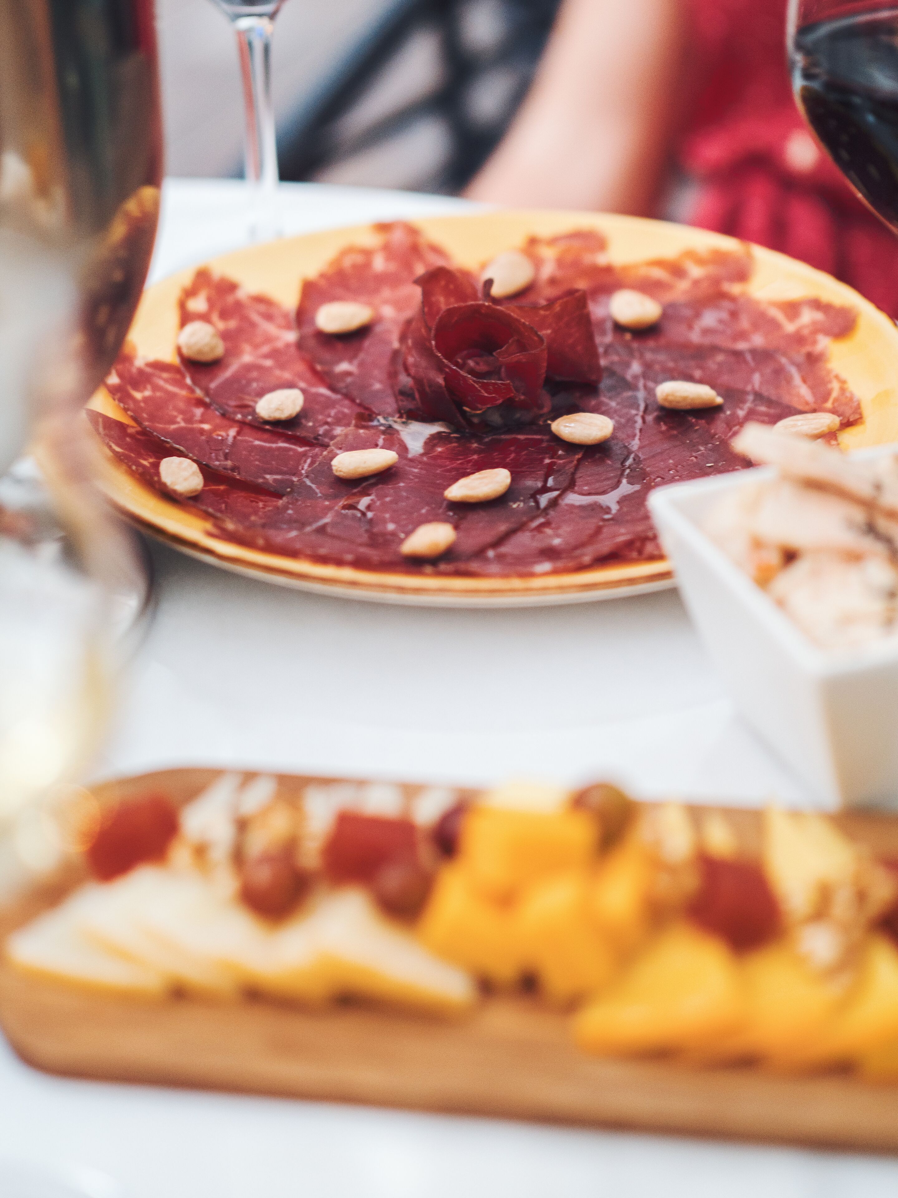A plate of sliced meats and almonds on a table.