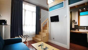 A modern living room with a sofa, a coffee table, a TV, and a staircase leading to an upper level.