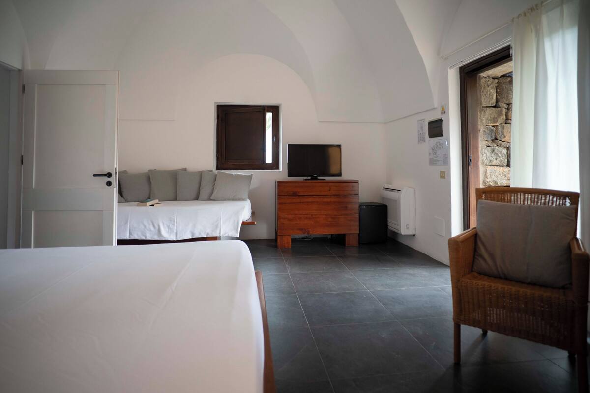 A bedroom with a bed, a dresser, a television, and a chair.