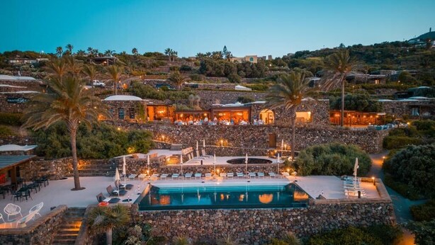 A resort with a pool, outdoor seating, and stone architecture.