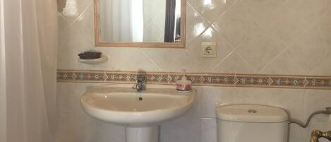 Un baño con lavamanos, inodoro y espejo.